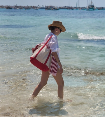 Woman walking by the beach carrying Lands’ End accessories and a tote bag
