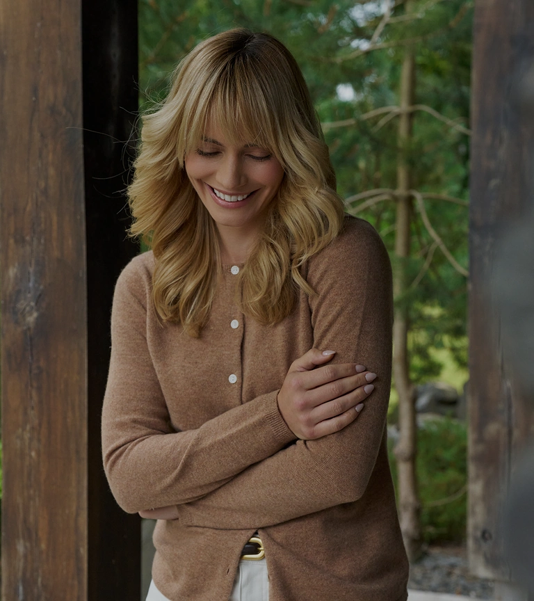 Woman wearing a brown cardigan and white trousers outdoors