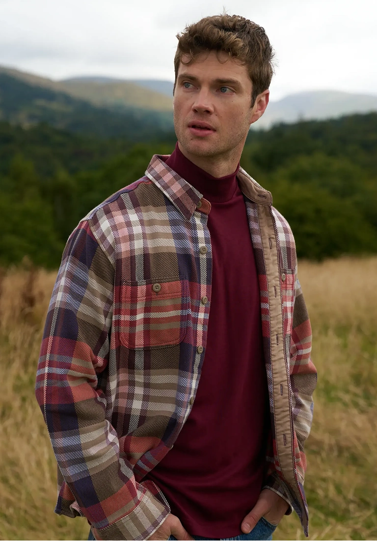 Man wearing a plaid overshirt and burgundy turtleneck outdoors