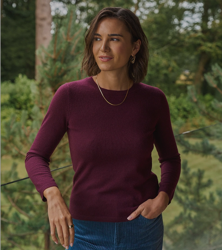 Woman wearing a burgundy jumper and blue jeans outdoors