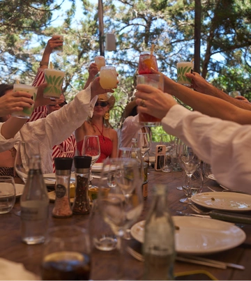 Group of friends raising their glasses together at a table in summer