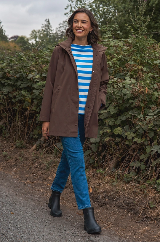 Woman wearing a lightweight raincoat, striped top and jeans