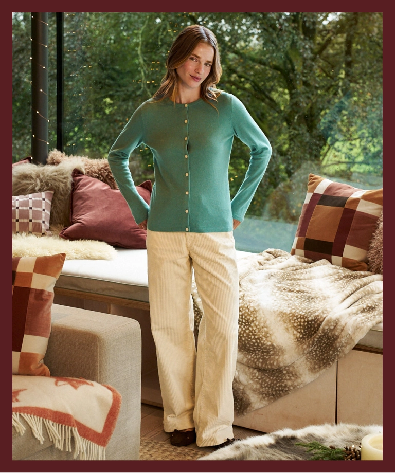 Woman wearing a green cashmere cardigan and cream trousers