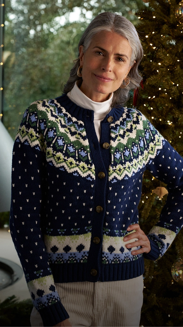 Woman wearing a navy Fair Isle cardigan in front of a decorated Christmas tree