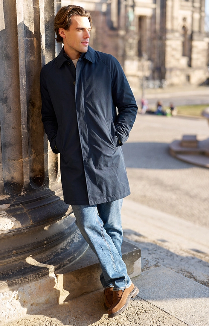 Man wearing a navy coat and jeans outdoors