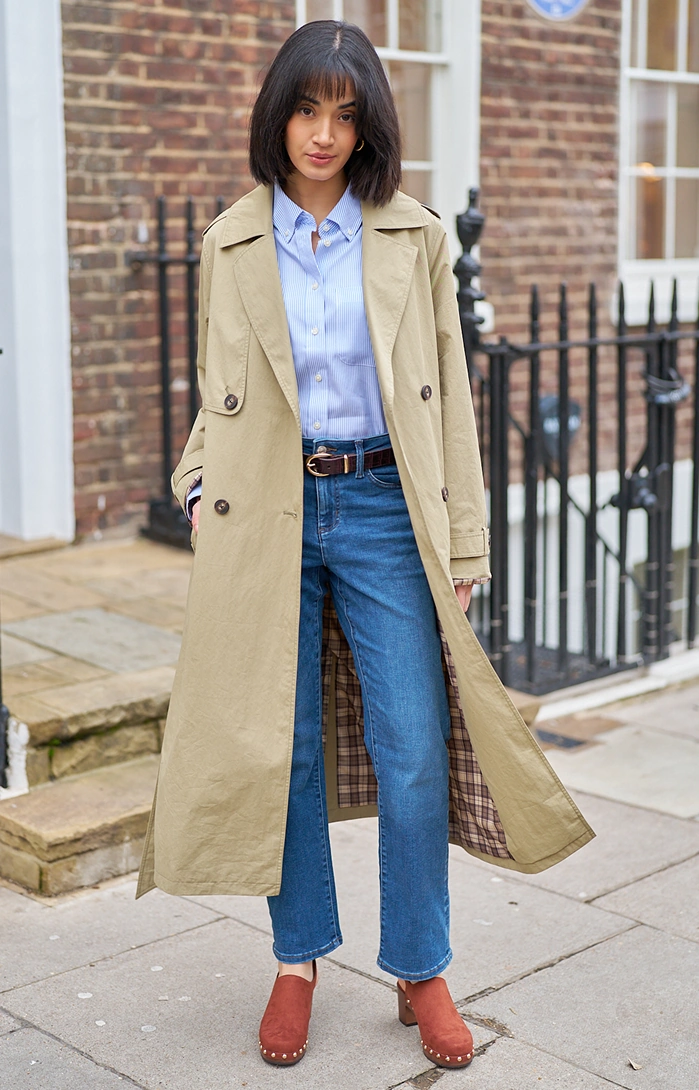 Woman wearing a trench coat, shirt and jeans outdoors